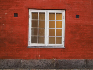 A red wall with a white window.