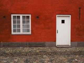 A red wall with a white window and door.