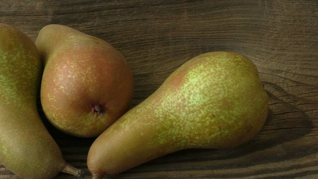 Three ripe juicy pears on a dark wooden table
