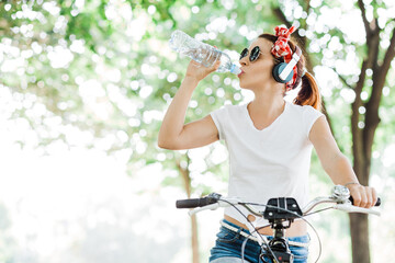 Naklejka premium Young woman drinking water sitting on the bicycle