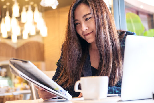 A business woman reading newspaper and drinking coffee in the morning in cafe