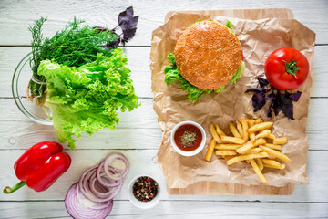 American hamburger with beef and french fries on wood table. Top view. Flat lay.