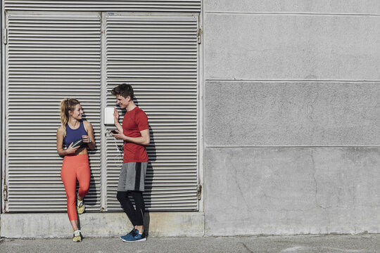 Pretty Caucasian sportswoman and handsome sportsman chatting adn standing outdoors.