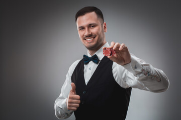 Young man in shirt and waistcoat shows his poker chips, studio shot