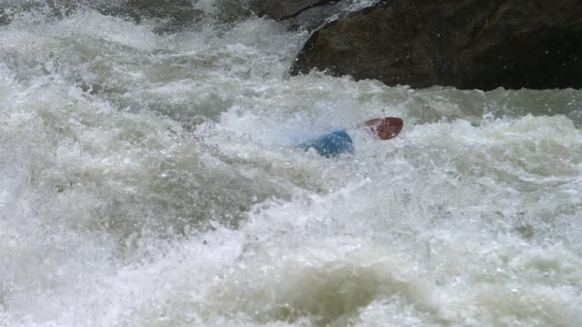 Extreme kayak bursting through rapids in slow motion
