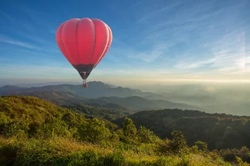 Poster Kleurrijke heteluchtballon over de berg bij zonsondergang © littlestocker