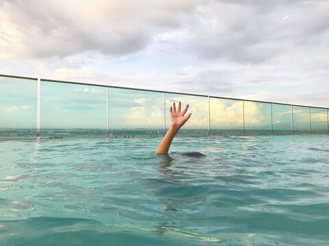 boy raising his hand from pool