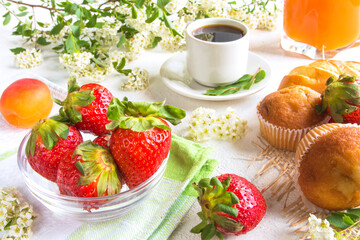 Breakfast with coffee, apricot juice, strawberry, fresh pastry muffin on whitecolored background concept of healthy food