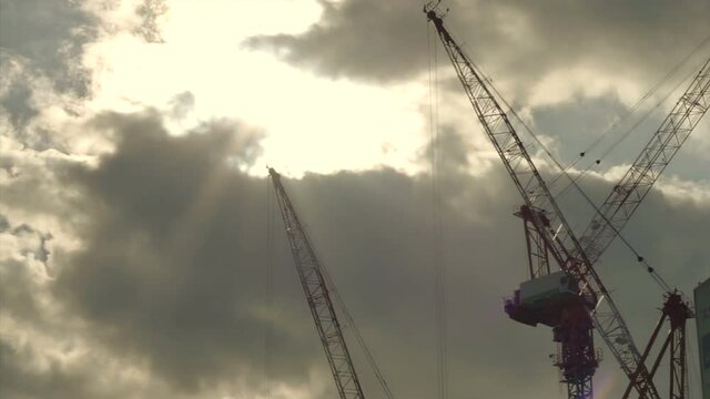 Construction cranes working in beautiful morning golden sun ray