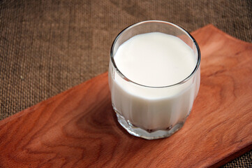 A glass of milk on wooden board on a background sacking, burlap, Copy space. Space for text.