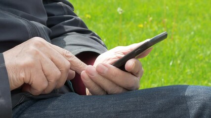 Elderly Man Sitting On Park Bench And Using Mobile Phone