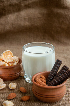 A glass of milk with almond nuts, corn flakes, chocolates,  on sacking background Copy space. Space for text.