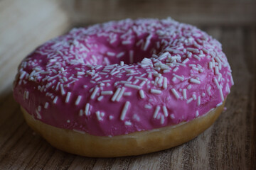 Sweet pink donut on wood plate