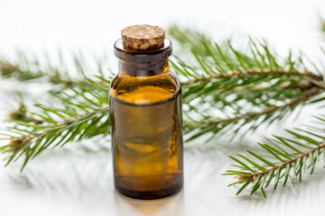 fir branches and spruce aroma oil on white table background