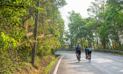 Naklejka premium Cyclist Asian men are cycling road bike morning uphill on the road in Chiang Mai Thailand