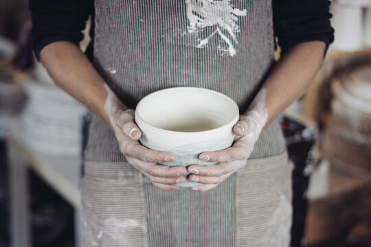 c&eacute;ramiste avec tablier et pot entre les mains