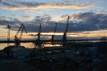 Cranes over the river in the port at sunset