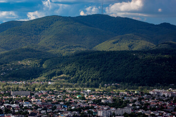 Fototapeta na wymiar little town on a plain among the mountains green hills