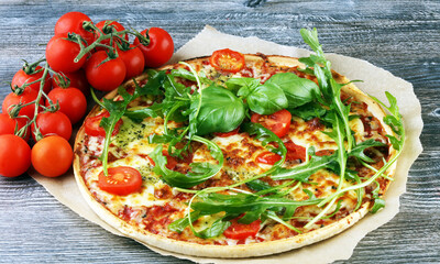 Hot true ITALIAN PIZZA with basil, arugula and cheese. TOP VIEW Tasty traditional pepperoni pizza on board on wooden table with decoration