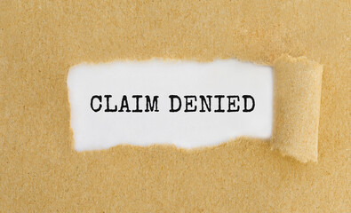 Text Claim Denied appearing behind ripped brown paper
