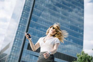 Young blond woman listening to music outdoors