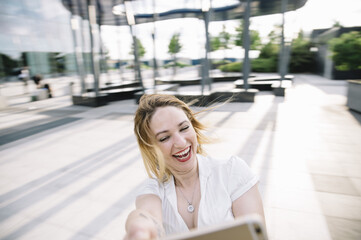 Young blond woman listening to music outdoors