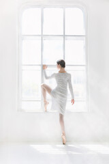 Fototapeta na wymiar Young and incredibly beautiful ballerina is posing and dancing in a white studio