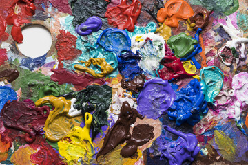 Painting pallet with thick texturized solid colorful paint looking like an abstract painting.