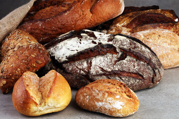 Different kinds of bread and bread rolls on board from above. Kitchen or bakery poster design.