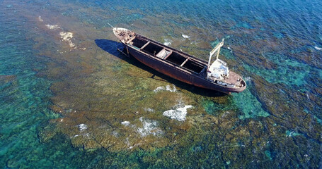 Fototapeta premium Beautiful seascape with old big, broken, rusty boat near the coast of Peyia, Cyprus. Ship graveyard. Famous landmark in the Mediterranean sea.