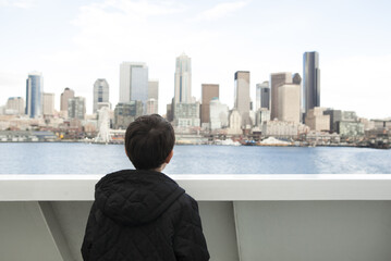 Boy on ferry looking at Seattle skyline