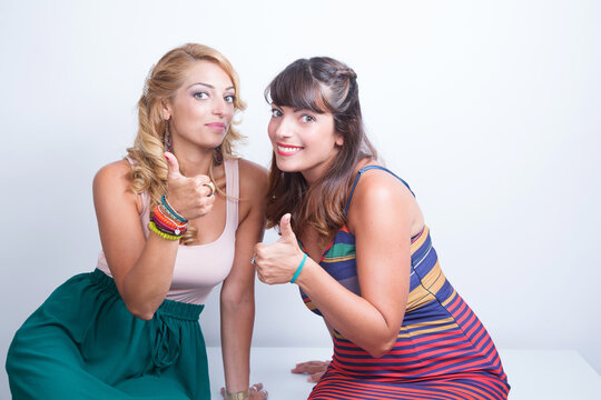 due gemelle, una bionda e una mora, fanno il segno okay con il polliceverso la macchina