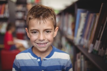 Portrait smiling schoolboy standing in library