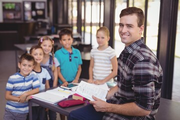 Portrait of teacher teaching schoolkids in library
