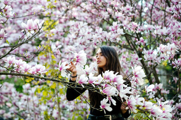 girl with long, brunette hair posing at magnolia tree