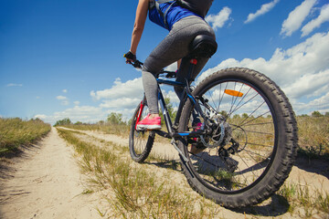 One young woman - an athlete rides on a mountain bike outside of town in a pine forest, on a summer day.