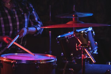 Female drummer playing drum set in nightclub - Powered by Adobe