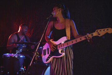 Obraz premium Female singer performing with male drummer in nightclub