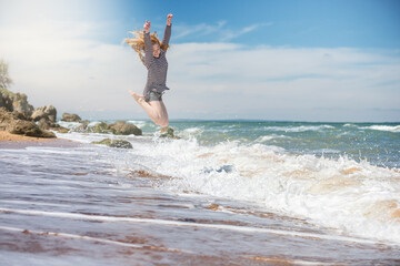 Beautiful sports young woman on a tropical ocean coast jumping high above the waves.