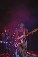 Obraz premium Singer playing guitar with male drummer in night club