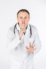 portrait of a male doctor doing shush gesture as silence or secret