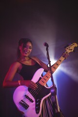 Obraz na płótnie Canvas Confident female singer holding guitar on stage in nightclub