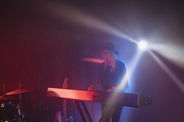 Female performer playing piano on illuminated stage