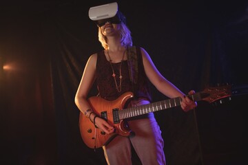 Obraz premium Guitarist experiencing VR glasses while performing in nightclub