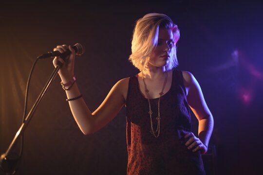 Female singer holding microphone in illuminated nightclub
