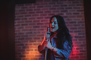 Cheerful singer singing illuminated nightclub