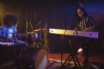 Singer and drummer performing in illuminated nightclub