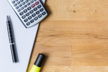 Work desk with note pad, calculator and biro on wooden table