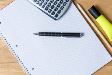Work desk with note pad, calculator and biro on wooden table