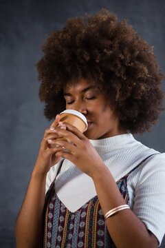 Close up of woman drinking coffee against wall